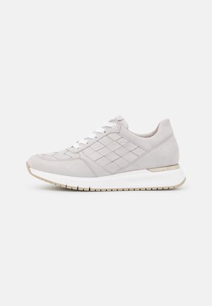 Jasnoszary, casual sneaker z białymi sznurowadłami, przeszywanym wzorem diamentowym po bokach i białą podeszwą z beżowym bieżnikiem, pokazany z lewej strony.