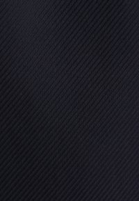 Gros plan d'un tissu noir avec un motif chevron diagonal fin et un tissage texturé.