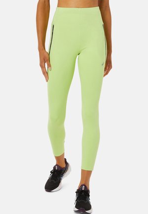Hellgrüne Leggings aus dehnbarem Stoff, mit schwarzen Reißverschlusstaschen an beiden Seiten und einem hohen Taillenbund für zusätzliche Unterstützung.