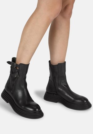 Zwarte leren enkelboots met een gestructureerde afwerking, voorzien van dubbele zijritsen en een stevige, ribbelige platformzool.