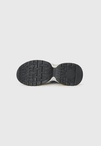 Shoe sole with a textured, black rubber design. Features distinct treads and a circular logo at the heel, providing grip and durability.