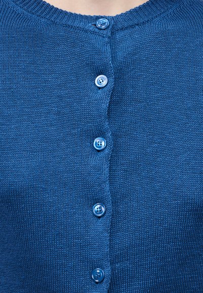 Μπλε πλεκτή ζακέτα με έξι ταιριαστά μπλε κουμπιά κλεισμένα μπροστά, εμφανίζοντας υφή πλεξίματος και στρογγυλή λαιμόκοψη.