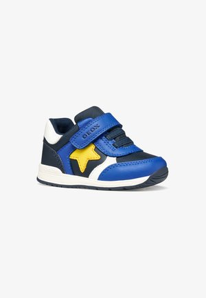 Scarpa da ginnastica per bambino piccolo in blu, nero e bianco con dettaglio a stella gialla, chiusura in velcro, lacci elastici e suola marchiata per uso quotidiano.
