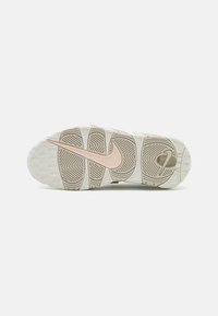 Semelle de sneaker Nike blanche avec un motif texturé, un logo rose proéminent et une caractéristique de coussin d'air. Design de semelle circulaire et ondulée.