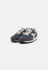 Marineblaue und graue Sneakers aus Wildleder und Mesh-Materialien, mit cremefarbenen Schnürsenkeln, weißen Akzenten und einer strukturierten Gummisohle.