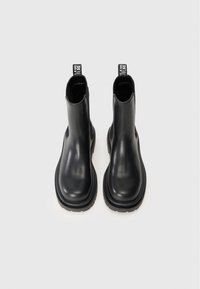 Black ankle boots made of smooth leather, featuring a rounded toe, side cutouts, and a textured rubber sole. Contrasting pull tab at the back.