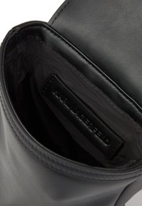 Fekete bőr táska sima külső felülettel, szövet bélelt belső térrel és márkázott bőrcímkével. Minimális design, strukturált forma.