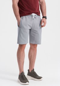 Bermudas de mezcla de algodón grises con cintura elástica y cordón blanco, con bolsillos laterales y un ajuste relajado.