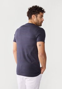 Camiseta de rayas azul marino de algodón, con mangas cortas y escote redondo, de forma ajustada y textura suave.