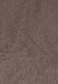 Teksturowana tkanina w stłumionym odcieniu mauve, o miękkim, dzianinowym wyglądzie i nieco nieregularnej powierzchni, sugerująca ciepło i komfort.
