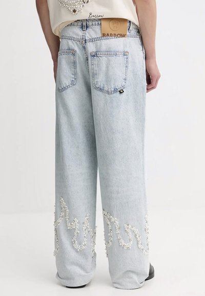 Jeans a gamba larga in denim blu chiaro con grandi tasche posteriori e dettagli in perline bianche decorate lungo l'orlo. Etichetta in pelle visibile in vita.