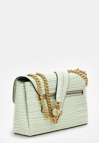 Kabelka mint zelené barvy s krokodýlím vzorem, zlatým řetízkovým popruhem a zipovým detailem. Má strukturovaný tvar s klopou a kontrastními černými okraji.