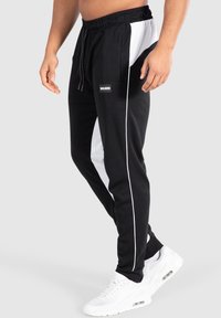 Svarta joggingbyxor med vita sidopaneler och kontrasterande vita pipings, med elastisk midja och logopatch framtill.