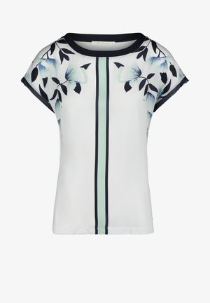 Halenka s květinovým vzorem, krátké rukávy, bílý základ, černé lemy a zelený vertikální pruh. Hladká tkanina s volným střihem.