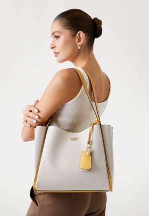 Grande borsa tote grigio chiaro con dettagli gialli e una finitura testurizzata. Presenta un logo dorato e un piccolo ciondolo staccabile.