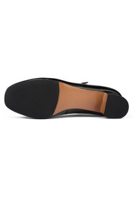 Sole di scarpa in pelle nera con una parte centrale liscia beige, caratterizzata da una base in gomma nera testurizzata per grip e stabilità.