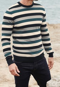 Pull en tricot avec des rayures horizontales en marine, bleu sarcelle, gris et crème. Présente un col rond et des poignets et un ourlet côtelés.