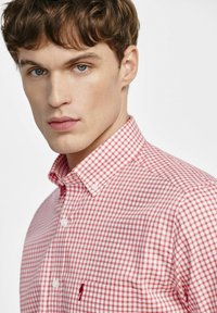 Czerwona i biała koszula w kratkę w stylu gingham z kołnierzykiem button-down oraz małym logo haftowanym na kieszeni. Materiał bawełniany, gładka faktura.