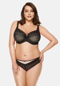 Czarny koronkowy biustonosz z zygzakowym wzorem, z wsparciem w postaci fiszbin oraz falbanką, w komplecie z pasującymi przezroczystymi majtkami bikini ozdobionymi kokardką.