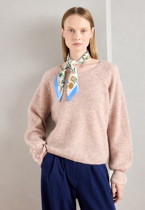 Lichtroze, fuzzy trui met een ronde halslijn, raglanmouwen en parelaccenten op de manchetten. Gecombineerd met marineblauwe broek en een zijden sjaal met bloemenmotief.