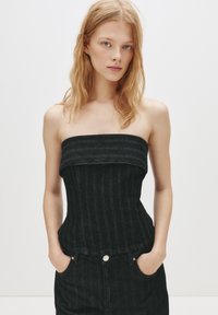 Top din denim negru fără bretele, cu o textură ribbed verticală și un design ajustat. Prezintă un decolteu drept și se află deasupra taliei.