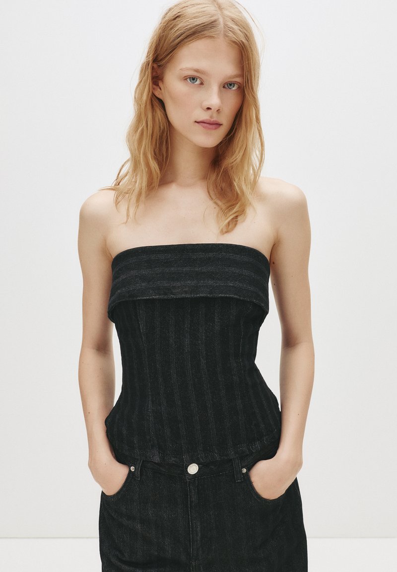 Top din denim negru fără bretele, cu o textură ribbed verticală și un design ajustat. Prezintă un decolteu drept și se află deasupra taliei.