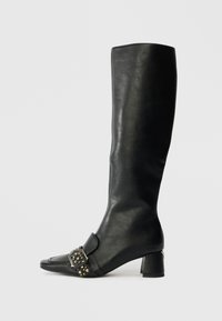 Knee-high black leather boot with a pointed toe, square buckle detail, and decorative studs; features a low block heel.