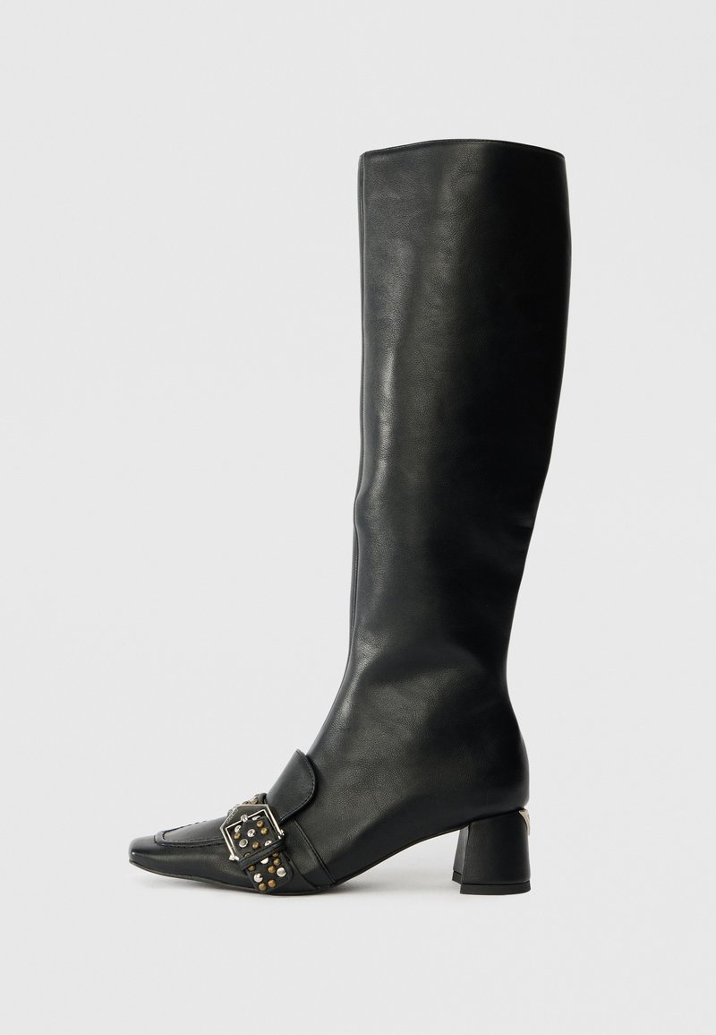 Knee-high black leather boot with a pointed toe, square buckle detail, and decorative studs; features a low block heel.