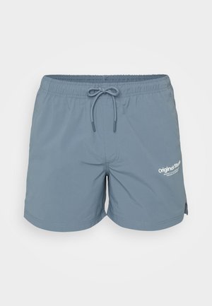 Lyseblå badetights laget av et glatt stoff, med elastisk midje og snøring samt en logo trykt foran.