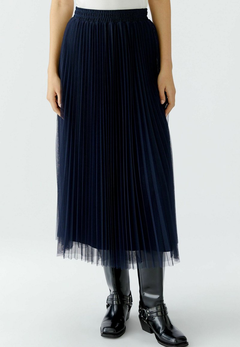 Jupe midi plissée marine en tissu de tulle, avec une taille smockée, un design en couches et une finition transparente et texturée.