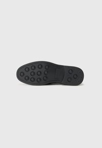 Schwarze Schuhsohle mit kreisförmigem Grip-Muster, aus Gummi gefertigt. Verfügt über erhabene, kreisförmige Akzente und ein flaches Absatzdesign. Einfach und funktional.
