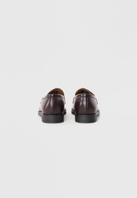 Chaussures habillées en cuir bordeaux avec une texture lisse, bout rond et semelle noire basse, présentant des coutures simples le long des coutures.