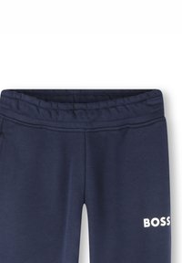 Pantalons de survêtement bleu marine avec une taille élastique. Présente le logo "BOSS" en blanc sur la jambe inférieure droite. Texture lisse et design ajusté.