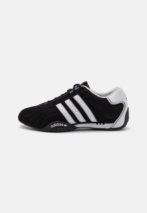 Lavprofils sort Adidas sneaker med hvide striber, sorte snørebånd og en hvid hælpatch, vist fra siden på en ensfarvet baggrund.