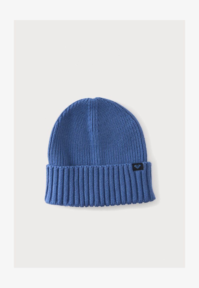Bonnet bleu tricoté avec bord-côte replié et petite étiquette noire affichant un logo en forme de cœur sur un fond clair uni.