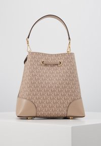 Sac seau beige avec un motif en logo MK répétitif, quincaillerie dorée, poignée courte et accents en cuir aux coins inférieurs.