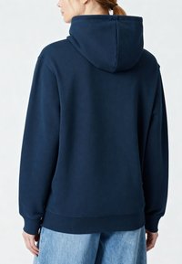 Sweat à capuche bleu marine avec une texture douce, doté d'une poche kangourou et de poignets côtelés. Coutures visibles au dos.