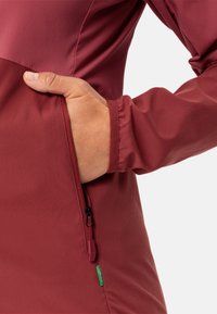 Maroon jacket featuring a zippered pocket and elastic sleeve cuffs, made from a smooth, lightweight fabric with a simple design.