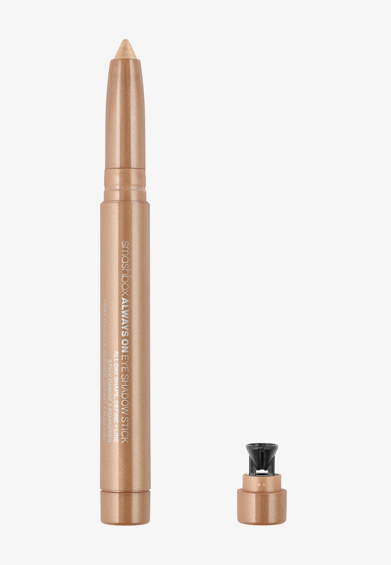 Guldmetallic øjenskygge-stift med spids tip, der har et sort dreje låg. Glat tekstur og cremet design for nem påføring.