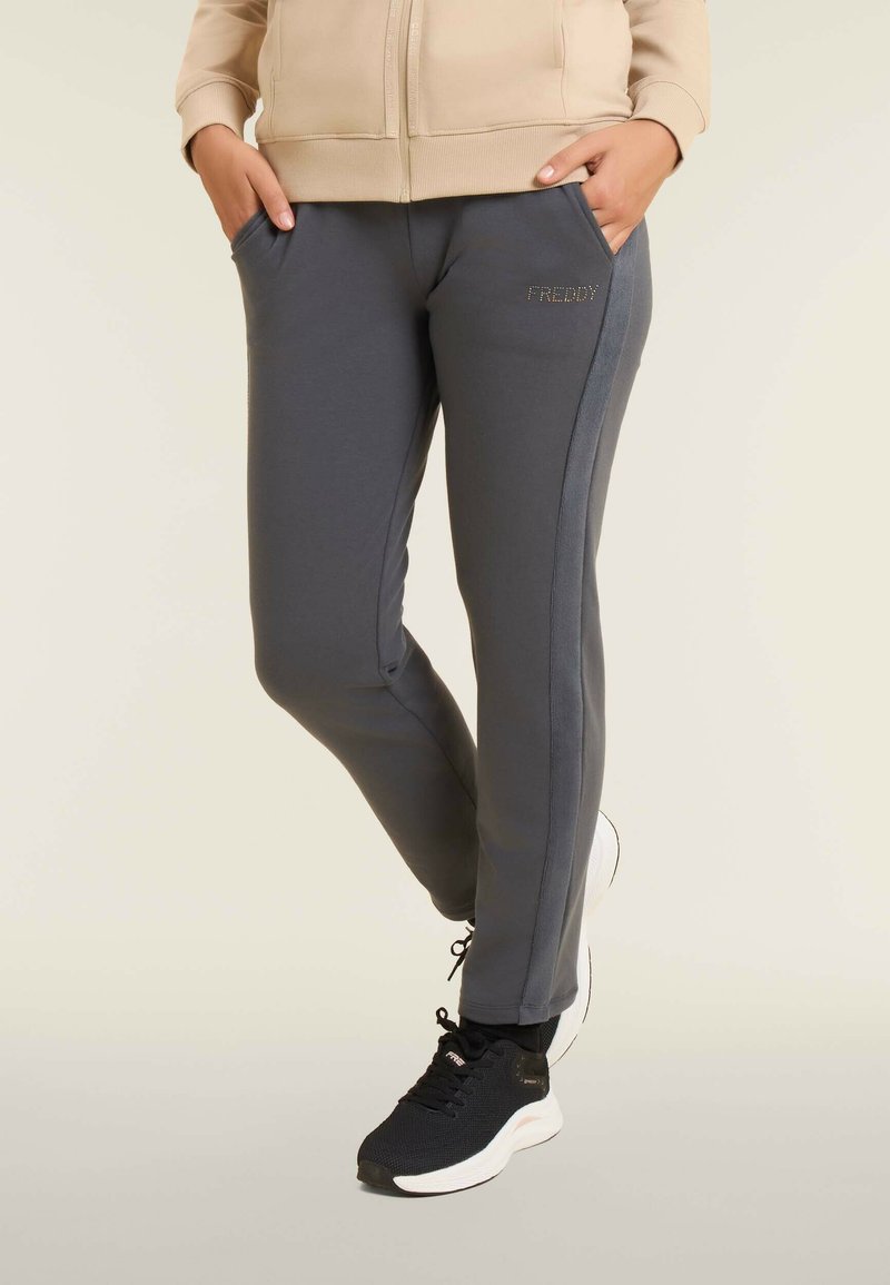 Pantalones de chándal grises de corte ajustado, con bolsillos laterales y un ligero brillo. Presentan el logo "FREDDY" en strass en el lateral.