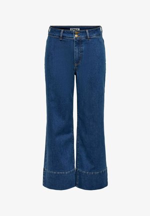 Modré rifle s vysokým pasem, širokými nohavicemi a zkrácenou délkou, s dvojitým zapínáním na knoflíky a logem na vnitřním pasu.