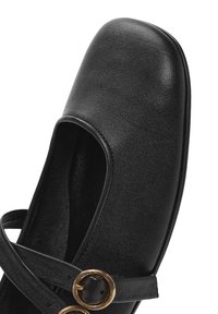Scarpa in pelle nera con punta quadrata, design a fascia incrociata e dettagli in metallo dorato. Presenta una superficie testurizzata e una suola piatta.