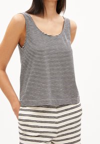 Svart- och vitrandig tanktopp med rundad halsringning och ärmlös design. Tillverkad av lätt material, matchas med randiga underdelar.