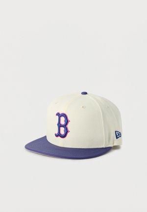 Șapcă de baseball albă cu margine mov, nasture mov în partea de sus și un „B” stilizat în culorile mov și roz pe panoul frontal.