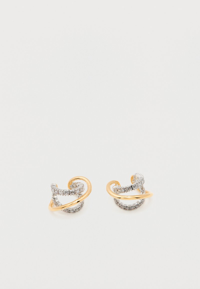 Paire de boucles d'oreilles créoles torsadées en or et argent avec des pierres précieuses transparentes incrustées sur un fond blanc.