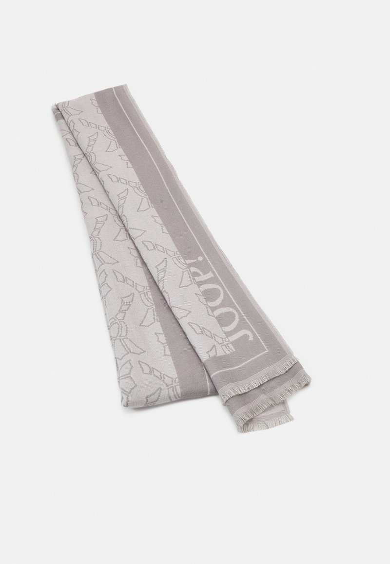 Écharpe gris clair avec un motif subtil, bords frangés et texture lisse. Présente un logo de marque bien visible sur un côté.