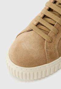 Baskets en suède tan avec bout rond, surface texturée, lacets plats et semelle en caoutchouc dotée de rainures verticales pour une meilleure traction.