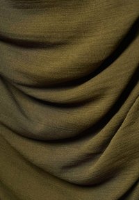 Olivno zeleno blago z gladko, mat površino, ki prikazuje drapirane gube, ustvarjajoče naravne razlike in globino v materialu.