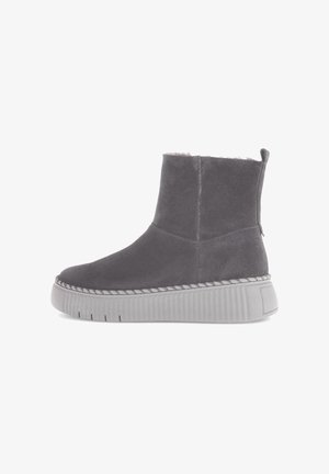 Stivale alla caviglia in suede grigio con punta rotonda, cuciture bianche in contrasto e una suola piatta spessa e testurizzata di colore grigio. Include una linguetta per il tiraggio.