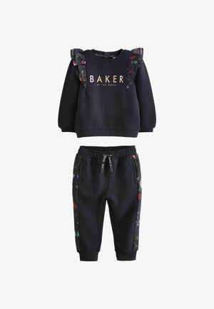 Námornícky modrý teplákový komplet s kvetinovými volánovými detailmi. Obsahuje mikinu s kulatým výstrihom a zúžené tepláky so bočnými vreckami a kvetinovou lemovkou.